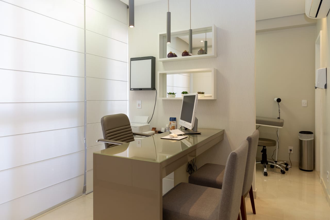 Consultório da Dra. Caroline, com mesa de atendimento e tons claros
